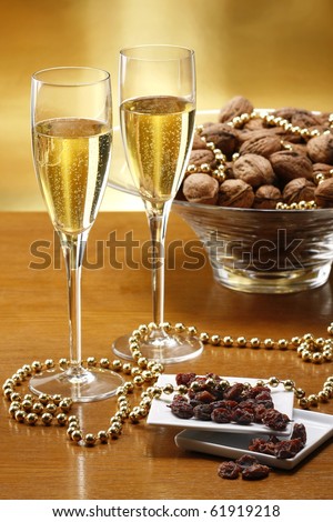 Glasses of champagne with gold background with walnuts, candels and dryed raisins