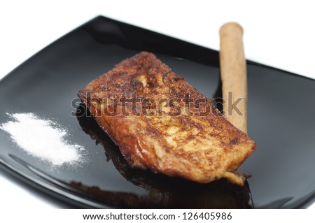 French toast, torrijas, and cinnamon stick on a black plate