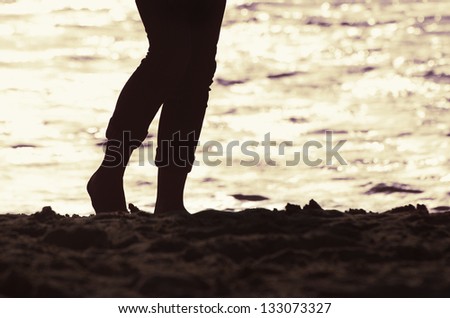 silhouette of a woman\'s legs on the beach during sunset