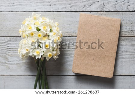 White narcissus flowers and notebook on wooden background