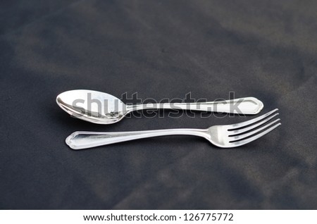 Close up of spoon and fork on black table linen.
