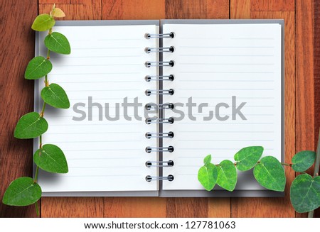 Open notebook with wood and green leaf background.
