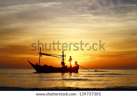 Silhouette of fisherman on boat in the sunrise, Hua Hin, Thailand