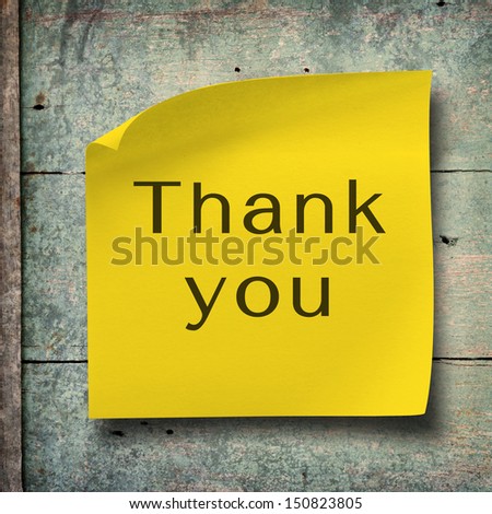 Thank you on yellow note paper with vintage grunge wood background