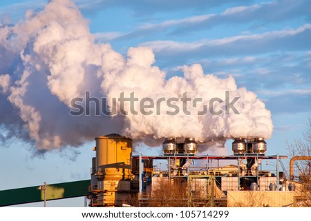 A A sugar mill factory creating smoke in front of a blue sky