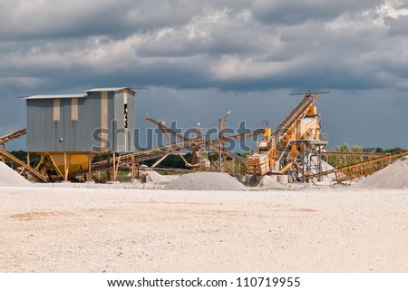 Gravel pit and Belt conveyors in summer in front of cloudy blue sky after storm