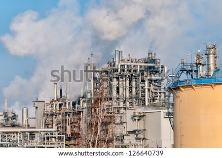 oil refinery with smoking chimneys in winter against blue sky