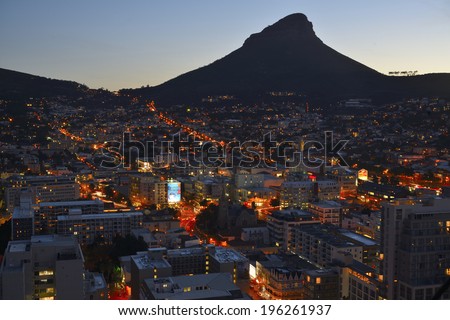 Evening view of Cape Town\'s landmark Lions Head with the residential suburbs at the foot of table Mountain illuminated. Kloof Nek on the left of Lions Head. Image captured on 23/05/2014