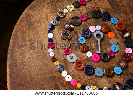 Set of vintage buttons on old wooden table with a key