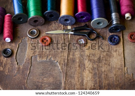 Spools of threads and buttons on old wooden table/Old sewing accessories