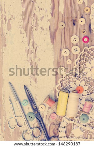 Vintage Background with sewing tools and colored tape/Sewing kit. Scissors, bobbins with thread and needles on the old wooden background