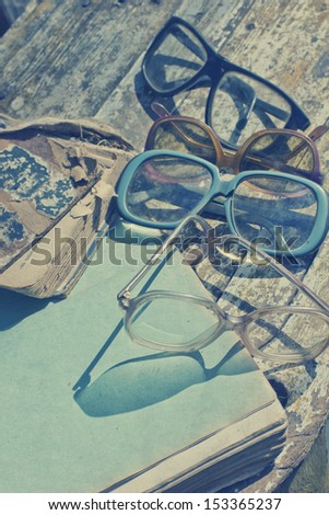 Close-up of opened book pages and glasses against vintage background/ Vintage books with reading glasses in an used bookstore