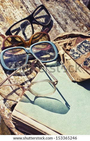 Close-up of opened book pages and glasses against vintage background/ Vintage books with reading glasses in an used bookstore