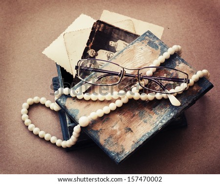 retro picture of a necklace lying on a book with glasses/ /romantic vintage background with and old pictures