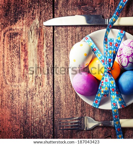 Easter table setting with white plate and easter egg on old wooden table/ Easter background