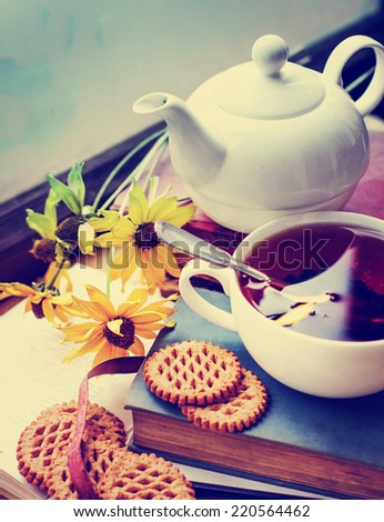 Autumn tea on old books with autumn flowers/ romantic autumn vintage background with books and tea/cookies with cup of black tea on wooden background