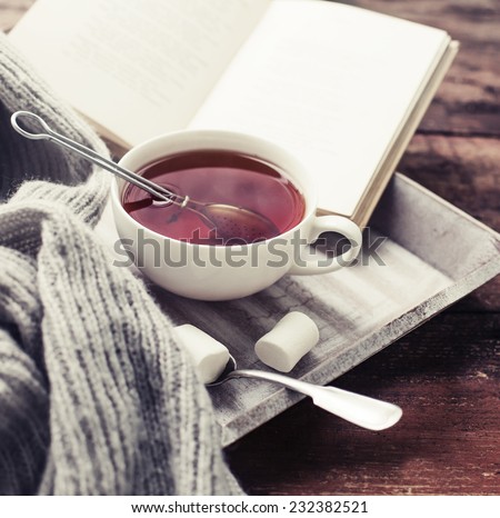 Warm knitted sweater,cup of hot tea and book on a wooden tray