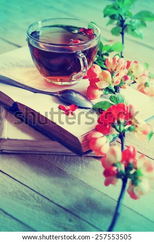 Books, flowers and cup of tea on wooden table.