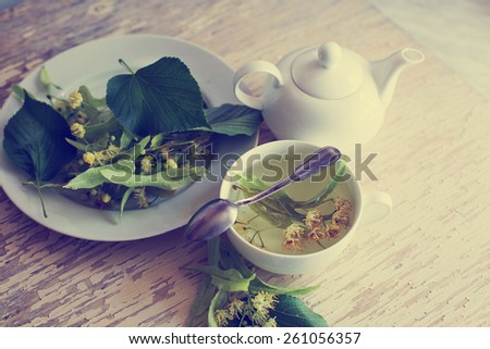 teapot and cup with linden tea and flowers on wooden table