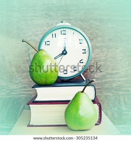 Alarm clock, book stack and felt pens. Schoolchild and student studies accessories. Back to school concept.