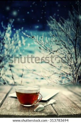 Hot tea cup on a frosty winter day window background/ Christmas holidays background/ Winter cozy background
