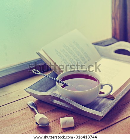 Warm knitted sweater,cup of hot tea and book on a wooden tray
