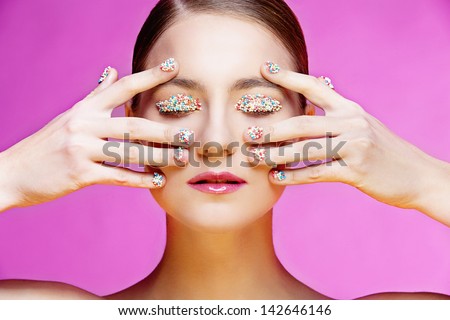 Closeup portrait of beautiful girl with colorful small candies on her nails and eyes