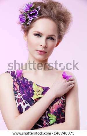 Portrait of beautiful girl in purple dress with butterflies and flowers in her fluffy hair