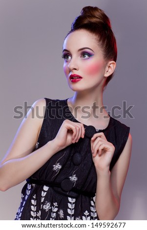 Beautiful girl with bright makeup in retro dress holding button