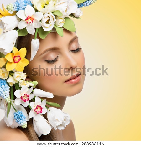 Closeup portrait of beautiful young woman with many flowers on head. Isolated over yellow background. Copy space, Square composition.
