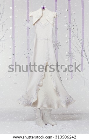 Beautiful custom made felt wedding dress on decorated hanger and boots over light grey background with purple ribbons, snowflakes