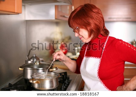 A middle aged woman stands in the kitchen cooking traditional Russian dish, pelmeni