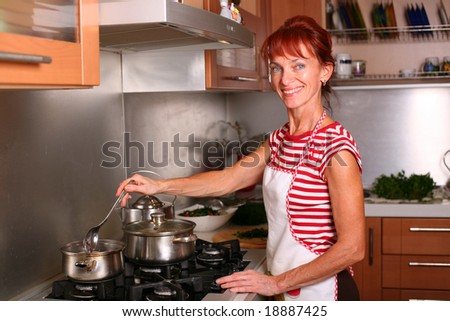 A smiling woman cooking dinner in the kitchen