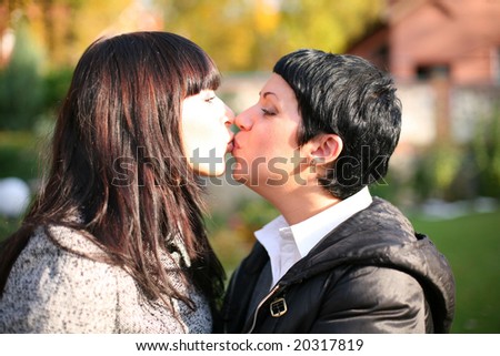Two smiling friends kissing each other standing in the garden