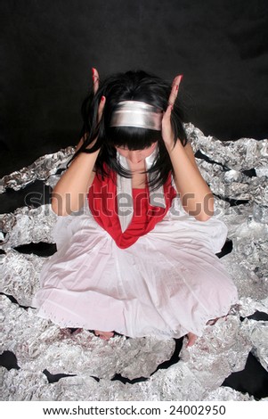 A young woman sitting among the foil over black background