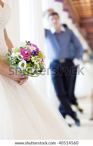 Bride holds a beautiful wedding bouquet. There is a silhouette of a groom on the background