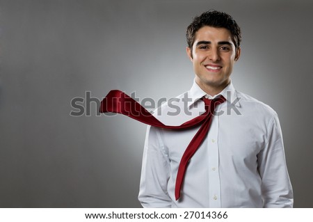Young businessman smiling at camera with blowing necktie. Good business in action!