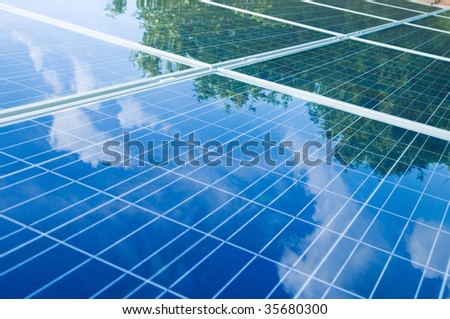 Green trees and blue sky reflection on solar panels. Go green with renewable energy!