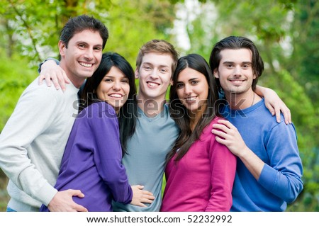 Young group of happy friends embracing and staying together outdoor in the park