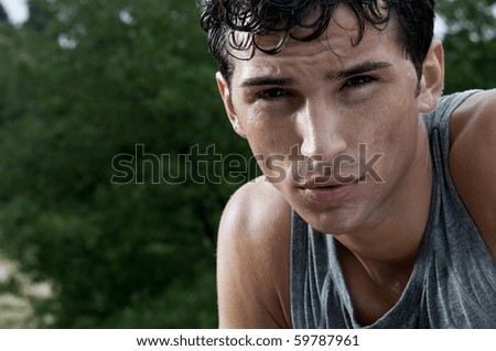 Young exhausted latin man looking at camera during a break of his outdoor jogging training