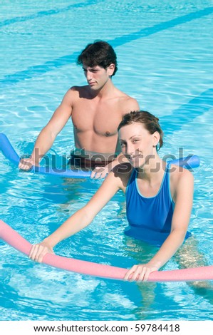 Happy smiling girl doing exercise with aqua tube in a swimming pool