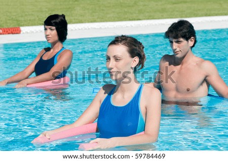 Happy active people exercising with aqua tube in water swimming pool