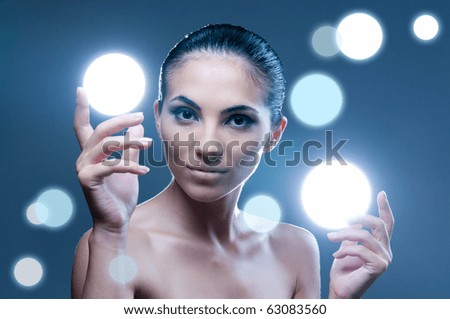 Beautiful fairy female model holding sphere of light on her hands, professional beauty makeup