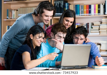 Absorbed young students watching at laptop and study together at college library