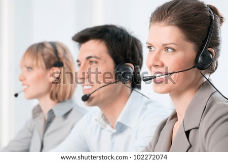 Smiling beautiful lady working at call center with colleagues in office