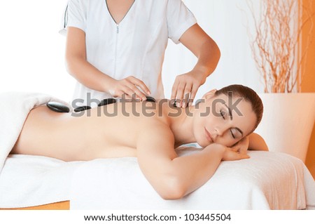Positioning warm stones on back for lastone therapy at spa center