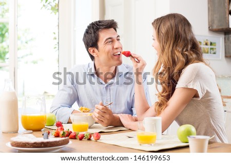 Portrait Of Happy Young Woman Feeding Strawberry To Man