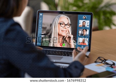 Multiethnic business team having discussion in video call. Rear view of business woman in video conference with boss and his colleagues during online meeting. Senior woman in video call with partners.