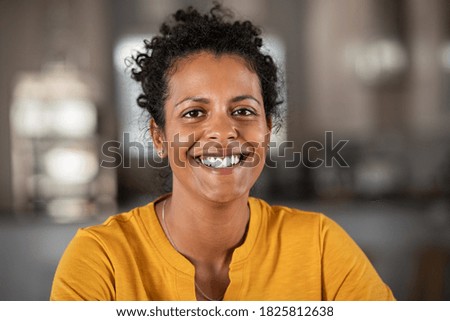 Portrait of a beautiful mid adult woman smiling at home. Middle aged african woman in casual looking at camera with copy space. Cheerful mixed race girl relaxing at home with big laugh.