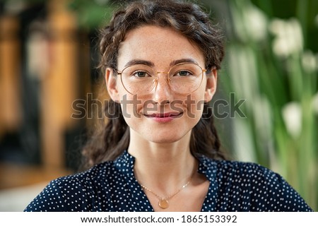 Portrait of young woman wearing spectacles and looking at camera. Close up face of happy girl with glasses smiling at work. Confident and satisfied businesswoman wearing eyeglasses in office.